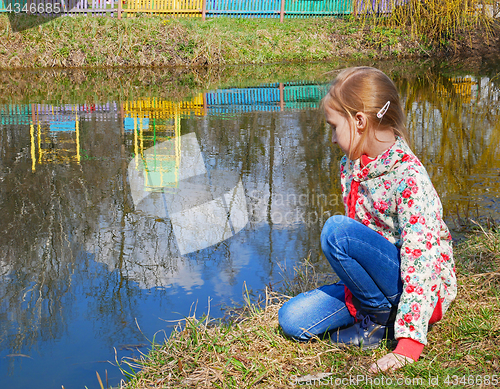 Image of Small girl sits near the lake
