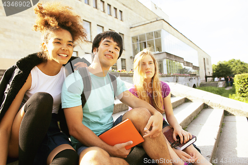 Image of cute group of teenages at the building of university with books huggings, back to school