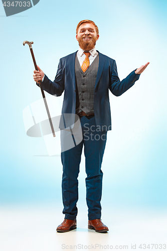 Image of The barded man in a suit holding cane.