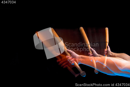 Image of The arm with wooden baseball bat on black background