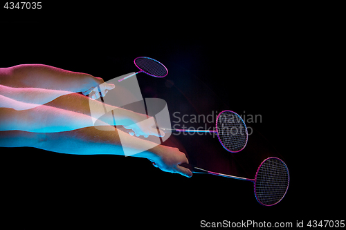 Image of The hands of young man playing badminton over black background