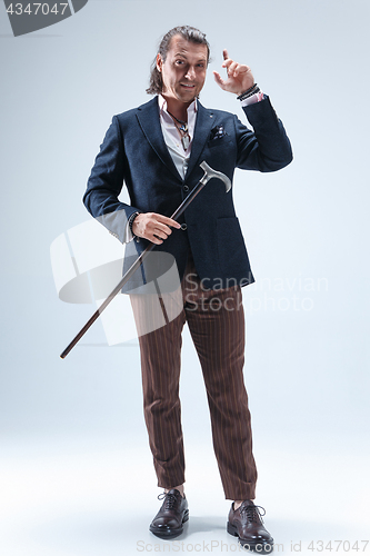 Image of The mature barded man in a suit holding cane.