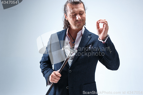 Image of The mature barded man in a suit holding cane.