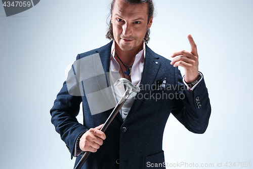 Image of The mature barded man in a suit holding cane.