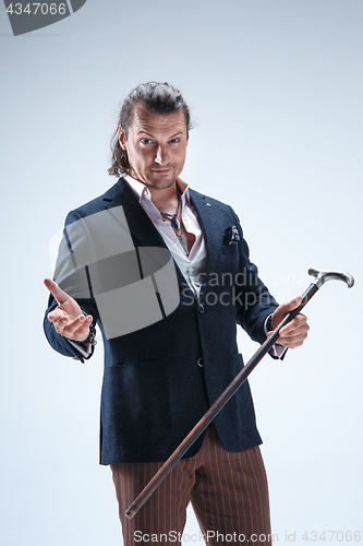 Image of The mature barded man in a suit holding cane.