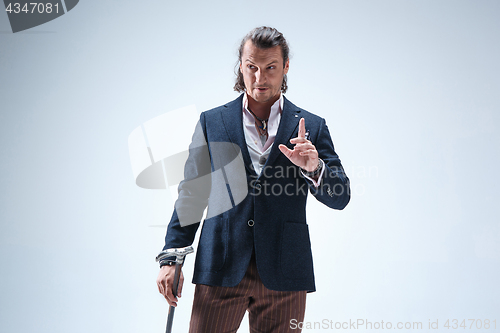 Image of The mature barded man in a suit holding cane.