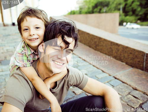 Image of little son with father in city hagging and smiling, casual look