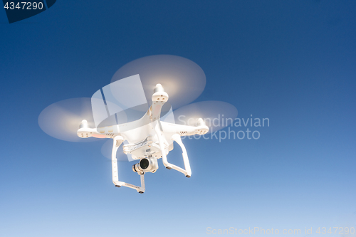 Image of White Quadcopter Drone Flying Hoovering Blue Sky