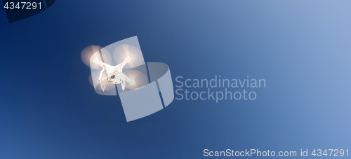 Image of White Quadcopter Drone Flying Hoovering Blue Sky