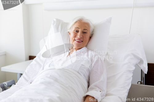 Image of smiling senior woman lying on bed at hospital ward