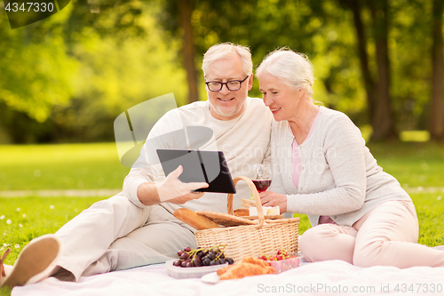 Image of happy senior couple having picnic at summer park