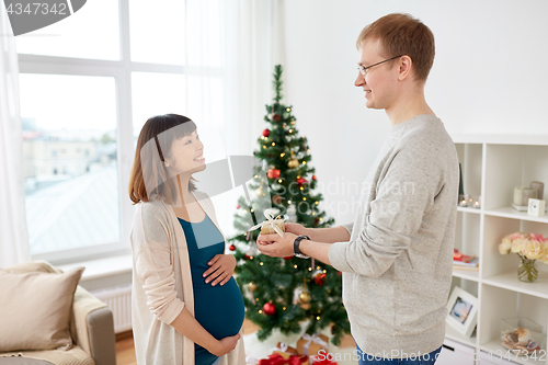 Image of husband giving christmas present to pregnant wife