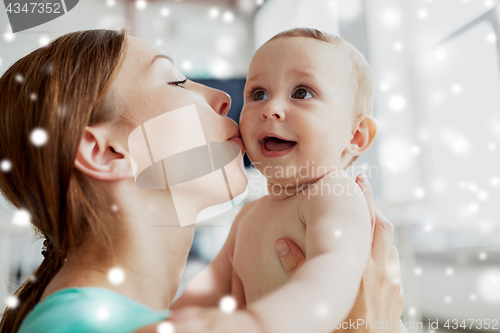 Image of happy young mother kissing little baby at home