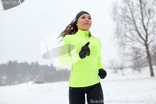 Image of happy woman running outdoors in winter