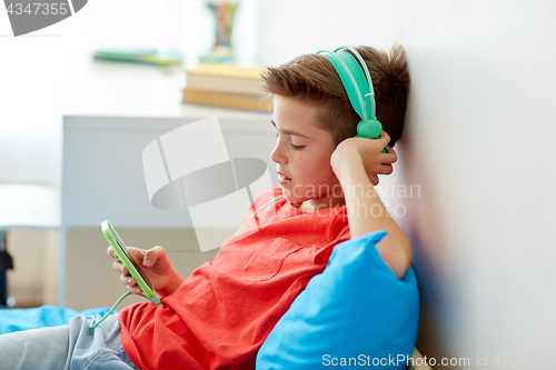 Image of happy boy with smartphone and headphones at home