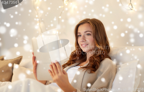 Image of happy young woman with tablet pc in bed at home