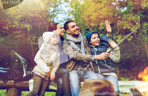 Image of family with smartphone taking selfie near campfire