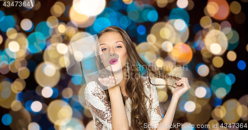 Image of happy woman sending air kiss over party lights