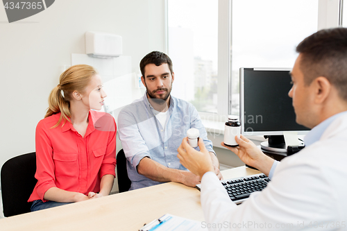 Image of doctor showing medicine to family couple at clinic