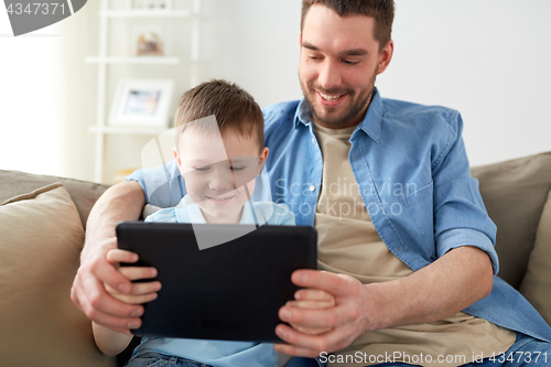 Image of father and son with tablet pc playing at home