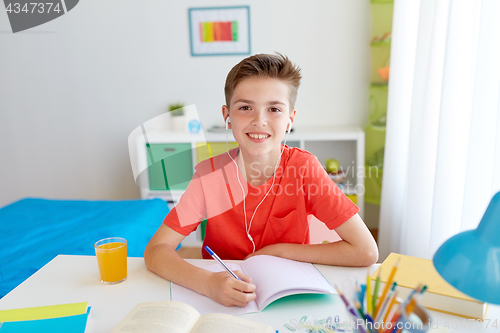 Image of happy student boy writing to notebook at home