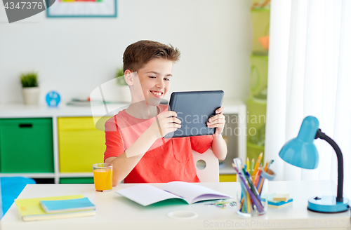 Image of student boy with tablet pc and notebook at home