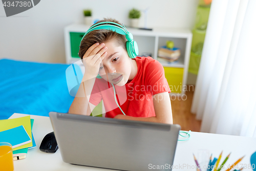 Image of boy in headphones playing video game on laptop