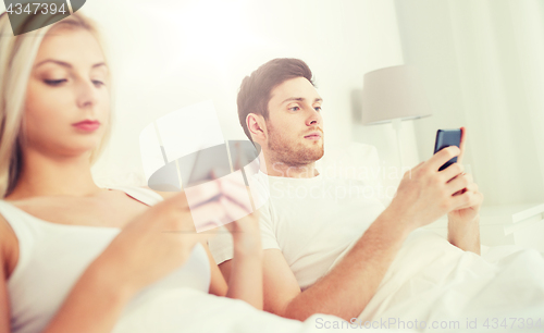 Image of couple with smartphones in bed