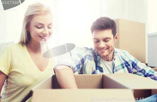 Image of smiling couple with big boxes moving to new home