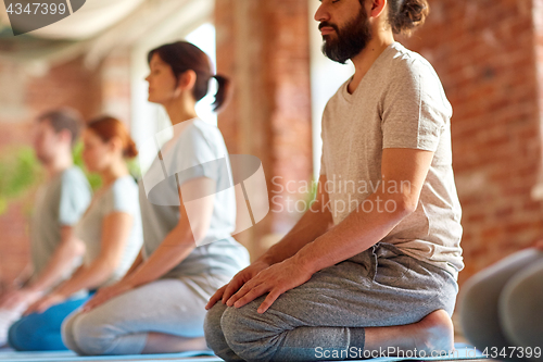 Image of group of people doing yoga kneeling pose at studio