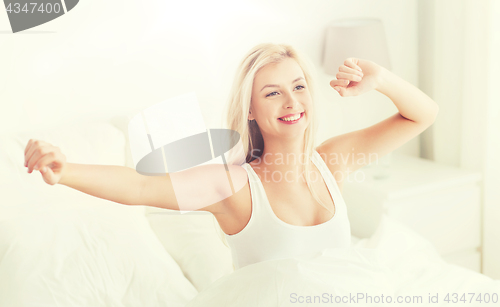 Image of young woman stretching in bed after waking up