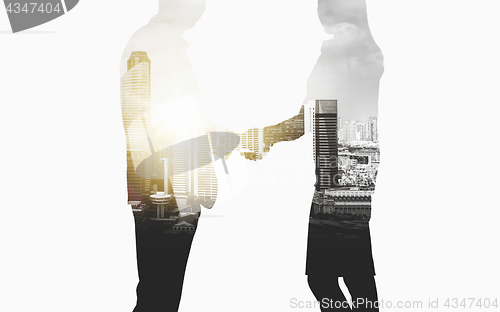 Image of business people shaking hands over city background