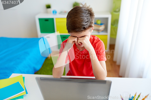 Image of tired student boy with laptop computer at home