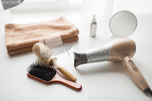 Image of hairdryer, hair brushes, mirror and towel