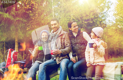 Image of happy family drinking hot tea at camp fire