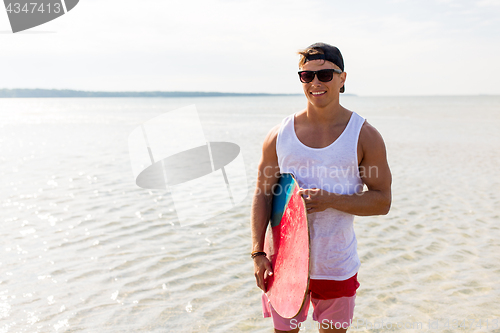 Image of happy young man with skimboard on summer beach