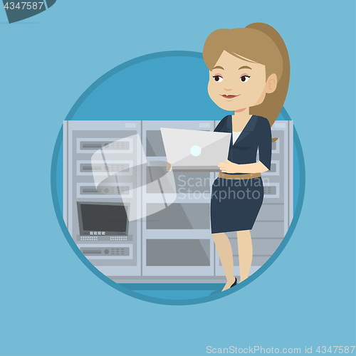 Image of Engineer working on laptop in network server room.