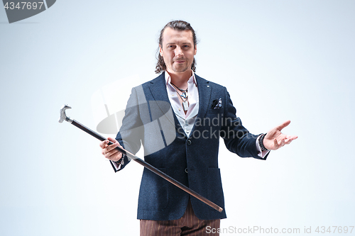 Image of The mature barded man in a suit holding cane.