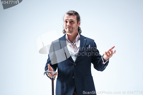 Image of The mature barded man in a suit holding cane.