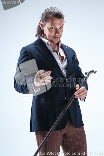 Image of The mature barded man in a suit holding cane.