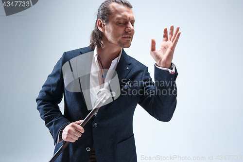 Image of The mature barded man in a suit holding cane.