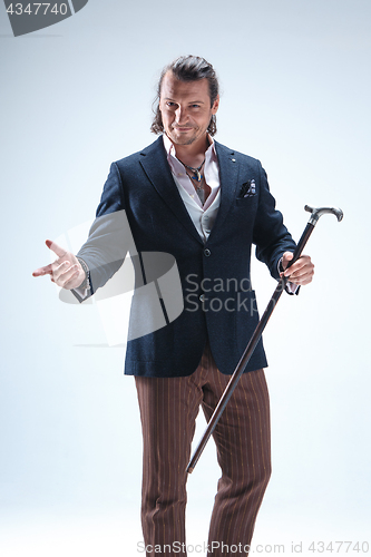 Image of The mature barded man in a suit holding cane.