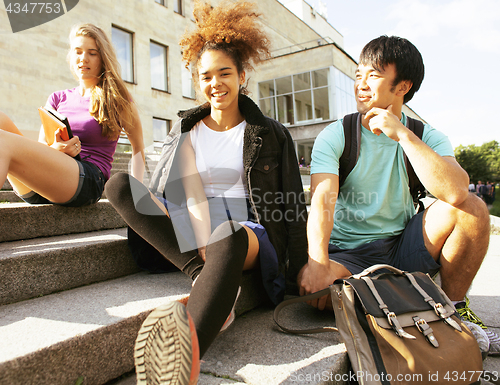 Image of cute group of teenages at the building of university with books huggings, back to school