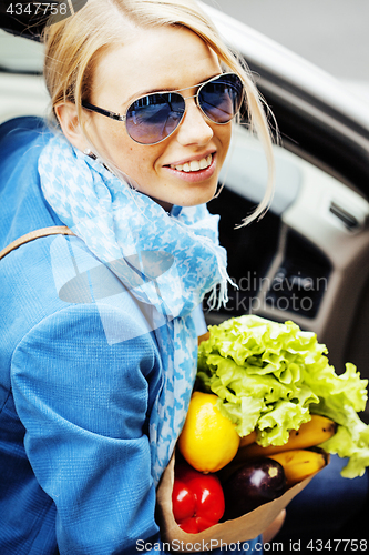 Image of young pretty blond woman with food in bag walking on street