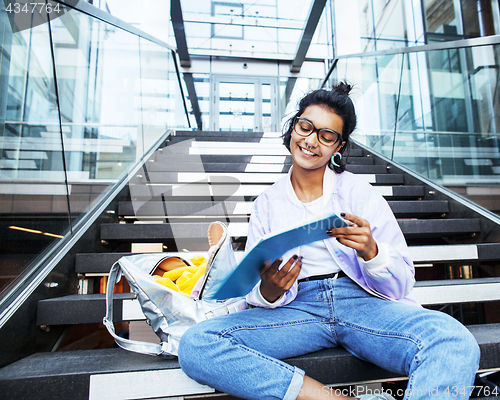 Image of young cute indian girl at university building sitting on stairs 