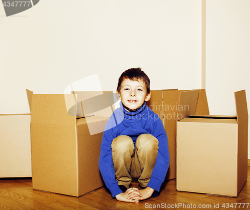 Image of little cute boy in empty room, move to new house. home alone among boxes close up kid smiling, lifestyle real people concept