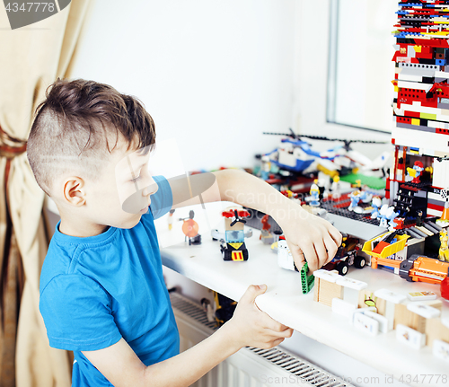 Image of little cute preschooler boy playing lego toys at home happy smil