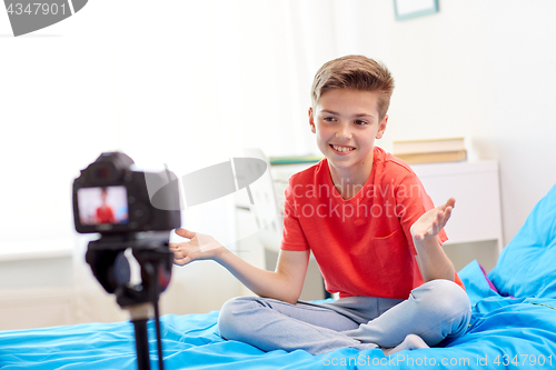 Image of happy boy with camera recording video at home