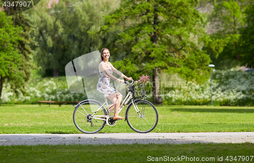 Image of happy woman riding fixie bicycle in summer park