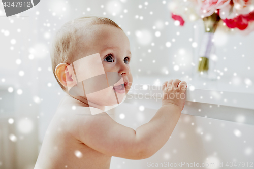 Image of happy little baby boy or girl holding to table